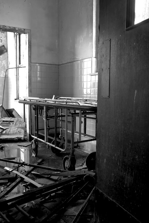 Abandoned tiled room with a medical gurney